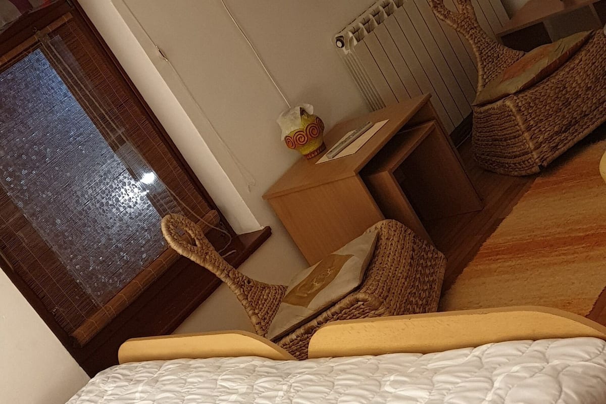 A bedroom with a bed, a desk, a chair, a lamp, and a window.