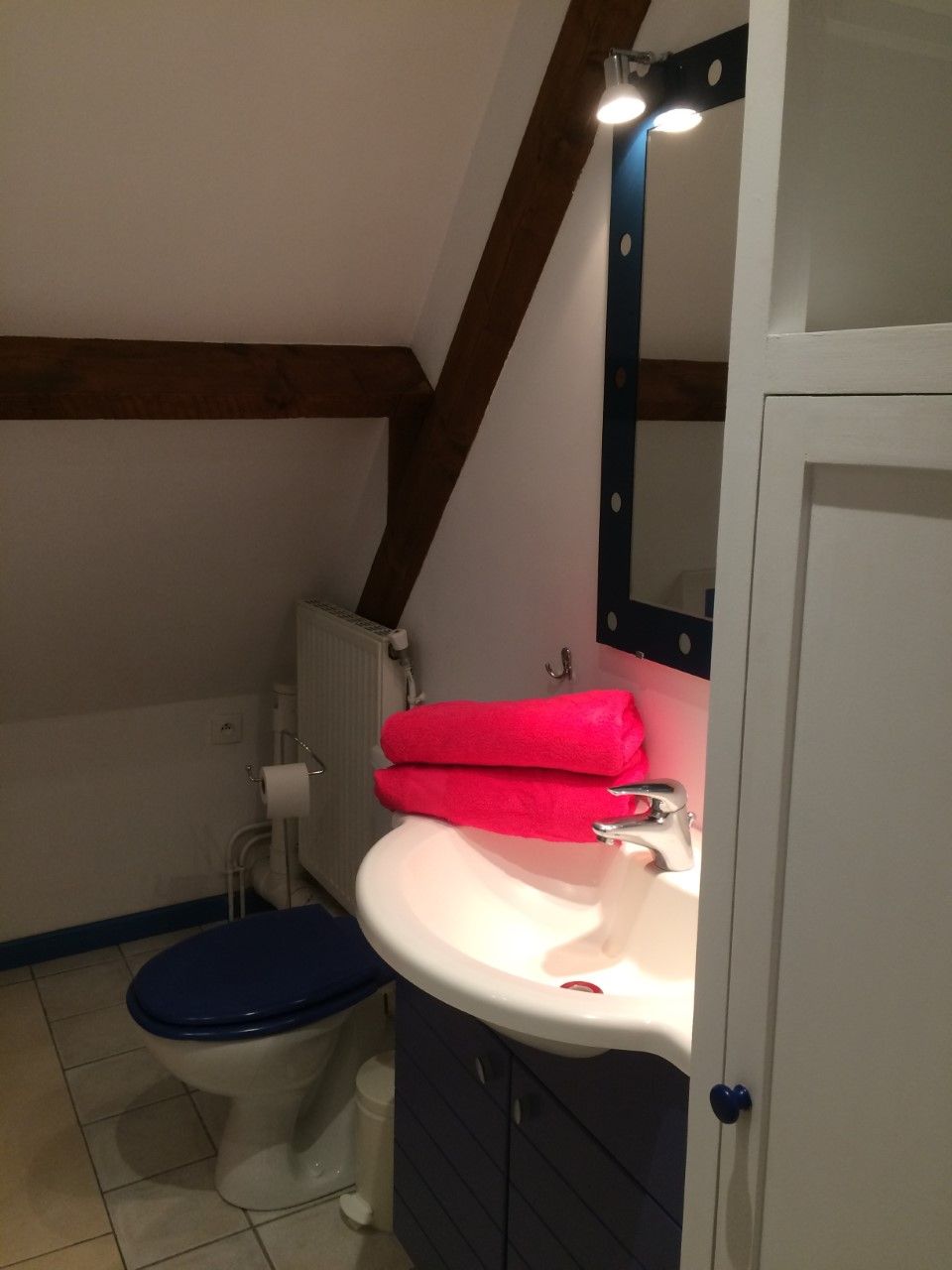Et lille badeværelse med toilet, håndvask og spejl.
