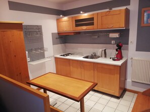 A compact kitchen with wooden cabinets, a stainless steel sink, and a small table. - DUPLEX WITH TERRACE  (Bonneville-la-Louvet)