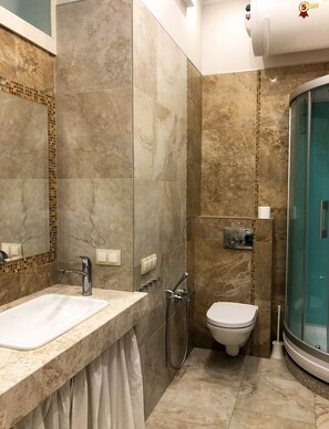 A bathroom with a large sink, a toilet, and a glass-enclosed shower.