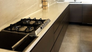 Een moderne keuken met een gasfornuis, donkere kastjes en een roestvrijstalen afzuigkap.