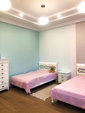 A bedroom with two beds, a dresser, and a nightstand.