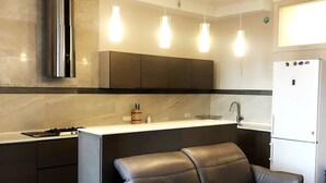 Een moderne keuken met een inbouwfornuis, een koelkast en hangende lampen.