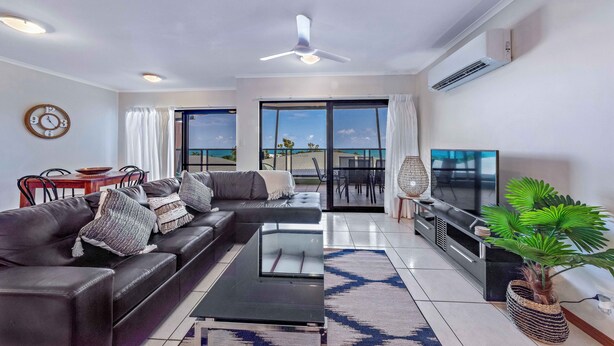 A modern living room with a sofa, coffee table, TV, and a balcony with a view.