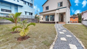 A two-story house with a covered porch and a small garden with palm trees. - Private Villa Espacio Onna (Onna)