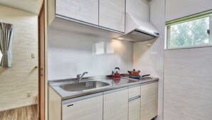 A modern kitchen with a stainless steel sink, a red kettle, and a window with a view of trees. - Private Villa Espacio Onna (Onna)