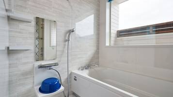 Ein modernes Badezimmer mit einer großen Badewanne, einer Dusche und einem Waschbecken mit einer blauen Seifenschale.