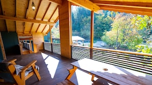 A wooden deck with benches and picnic tables, overlooking a forested area with a view of a parking lot and a white car. - Abant Villa Otel (Bolu)