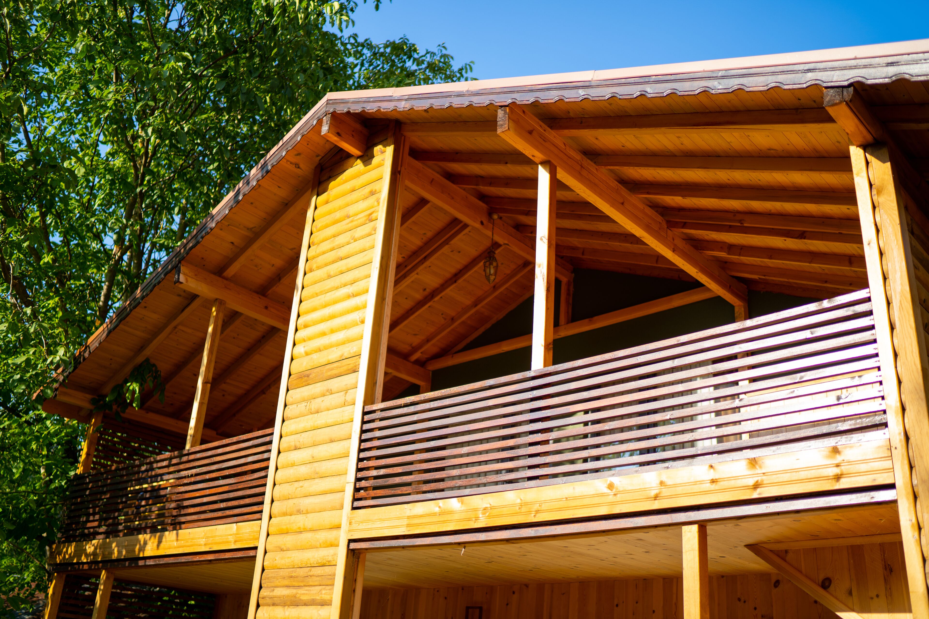 Een houten vakantiehuis met een balkon en een overdekte veranda.