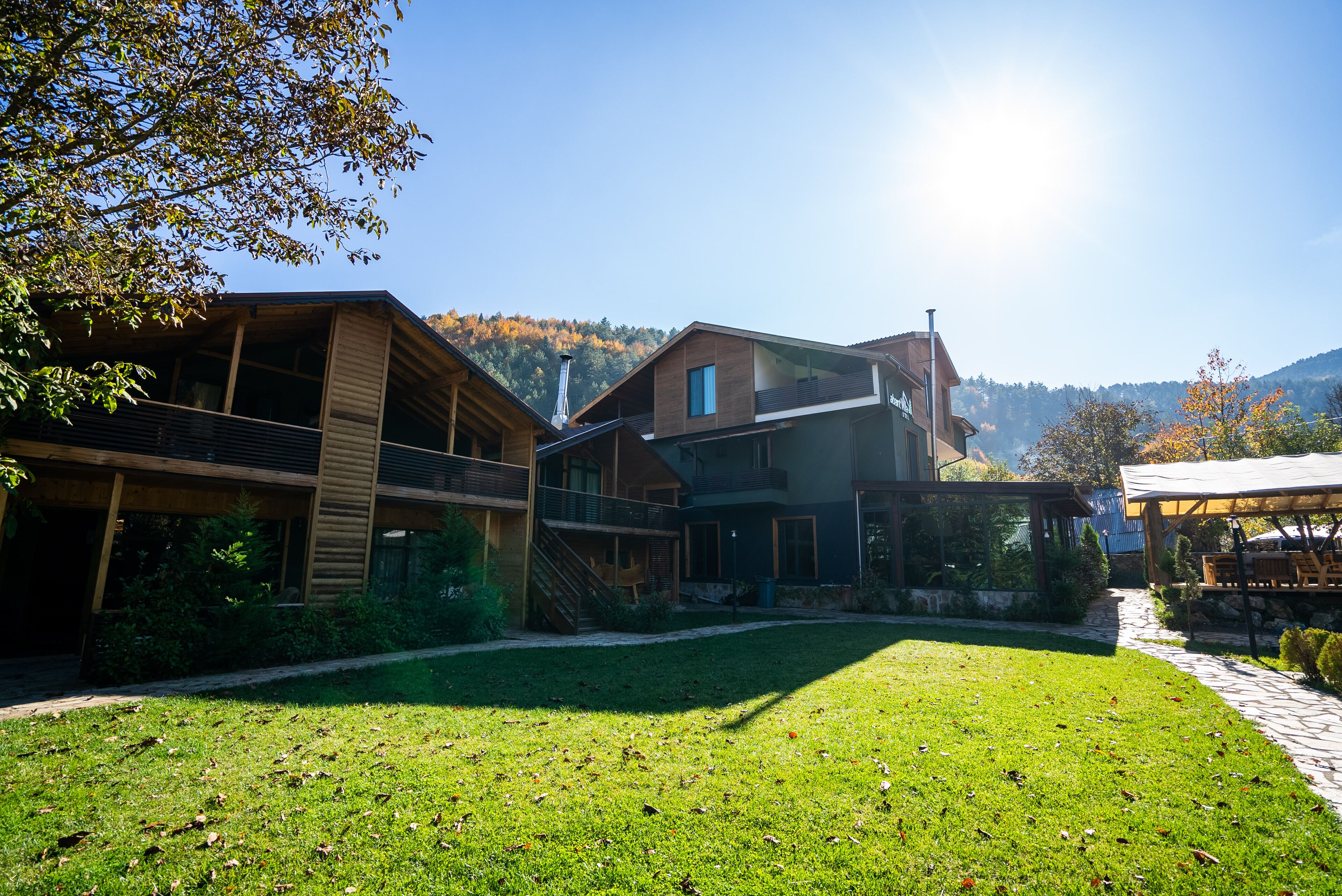 A modern building with a covered outdoor area, a grassy courtyard, and a mountain backdrop.