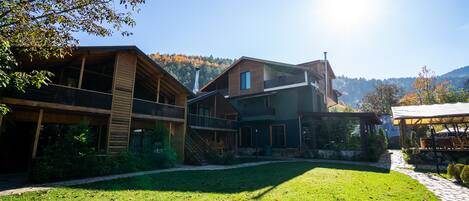 A modern building with a covered outdoor area, a grassy courtyard, and a mountain backdrop.