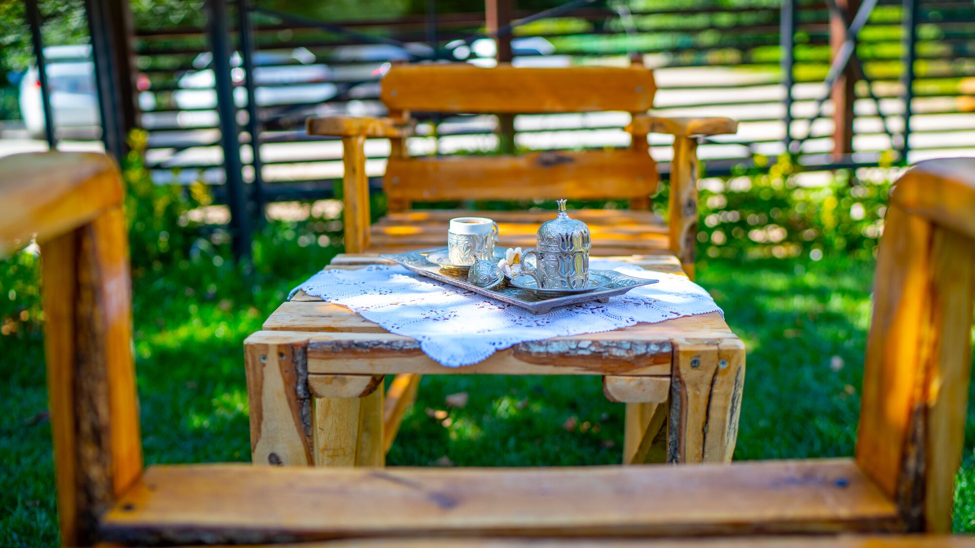 A wooden bench with a tray of silverware and a cup, set on a table with a lace doily.