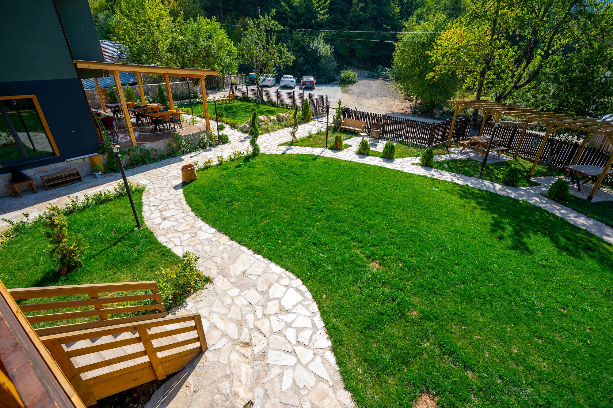 A modern outdoor area with a stone pathway, a grassy lawn, and wooden seating.