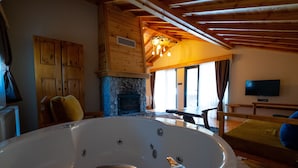 A room with a large bathtub, wooden walls, a fireplace, and a television. - Abant Villa Otel (Bolu)