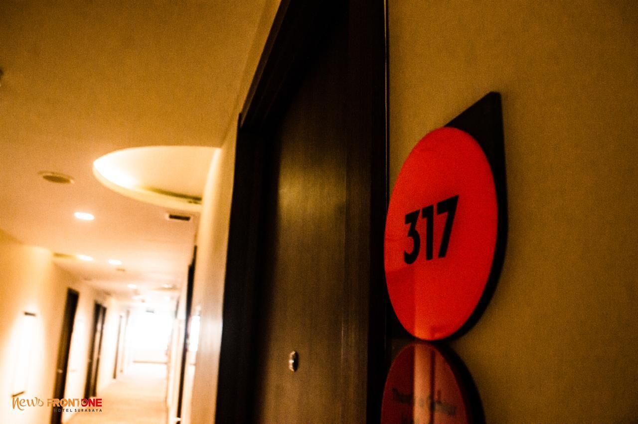 Corredor de hotel com uma porta identificada com o número 317 e uma placa indicando "News Frontone Hotel Surabaya".
