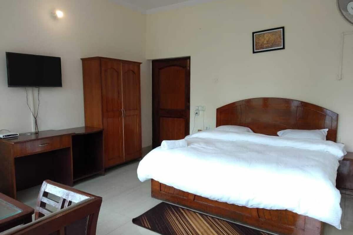 Un dormitorio con una cama de madera, un escritorio, una silla, un televisor y un armario.