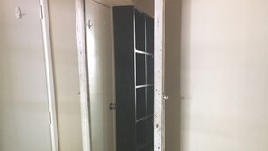 Habitación de esquina con una puerta blanca, un espejo alto con marco blanco y piso alfombrado.
