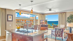 Una cocina moderna con una isla grande, un comedor con vistas al océano y un balcón con vistas al mar.