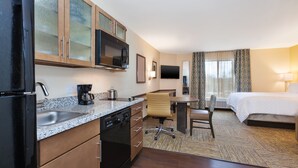 A hotel room with a kitchen area, a bed, a desk, and a TV. - Candlewood Suites Louisville - NE Downtown Area by IHG (Louisville)