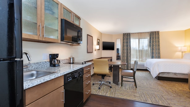 A hotel room with a kitchen area, a bed, a desk, and a TV. - Candlewood Suites Louisville - NE Downtown Area by IHG (Louisville)
