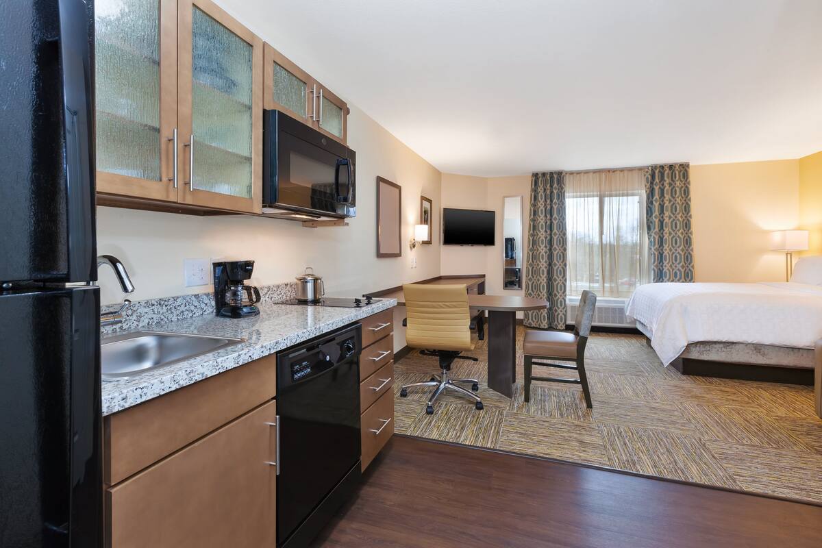 Une chambre d’hôtel équipée d’un coin cuisine, d’un lit, d’un bureau et d’une télévision.