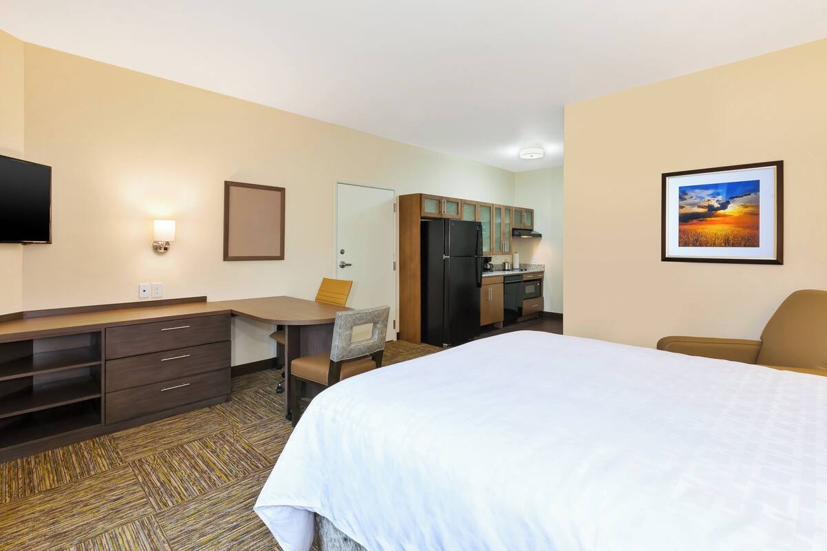 Une chambre d’hôtel équipée d’un lit, d’un bureau, d’une chaise, d’une kitchenette et d’un téléviseur.