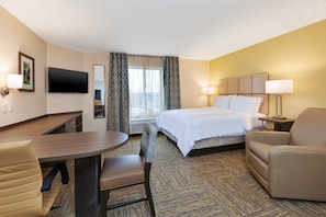 A hotel room with a bed, a desk, a chair, a TV, and a window with curtains. - Candlewood Suites Louisville - NE Downtown Area by IHG (Louisville)
