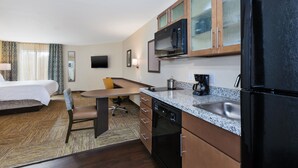 A hotel room with a bed, a desk, a chair, a microwave, a refrigerator, a sink, and a television. - Candlewood Suites Louisville - NE Downtown Area by IHG (Louisville)