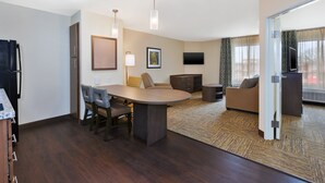A modern hotel room with a dining area, a sofa, a television, and a large window with curtains. - Candlewood Suites Louisville - NE Downtown Area by IHG (Louisville)