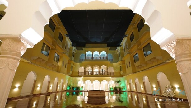 An interior courtyard with a central fountain, arched balconies, and a reflective pool. - Hotel Raj Bagh Palace (Amer)