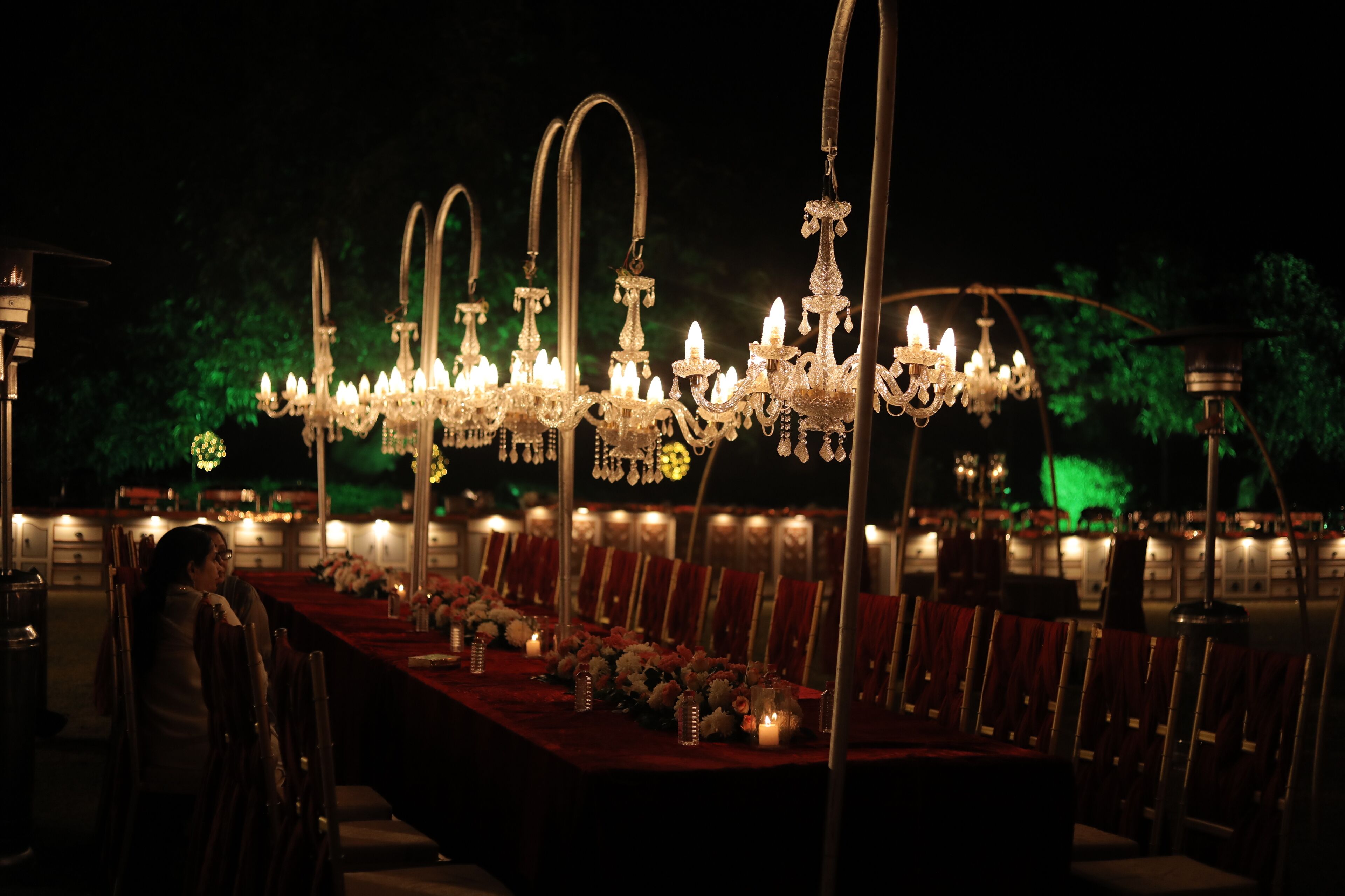 A banquet hall with a long table set for a formal event, adorned with candles and flowers.