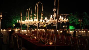 A banquet hall with a long table set for a formal event, adorned with candles and flowers.