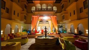 A courtyard with a fountain, seating areas, and a stage with draped curtains. - Hotel Raj Bagh Palace (Amer)
