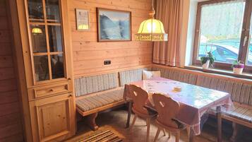 Een houten interieur met een eettafel, banken en een kast.