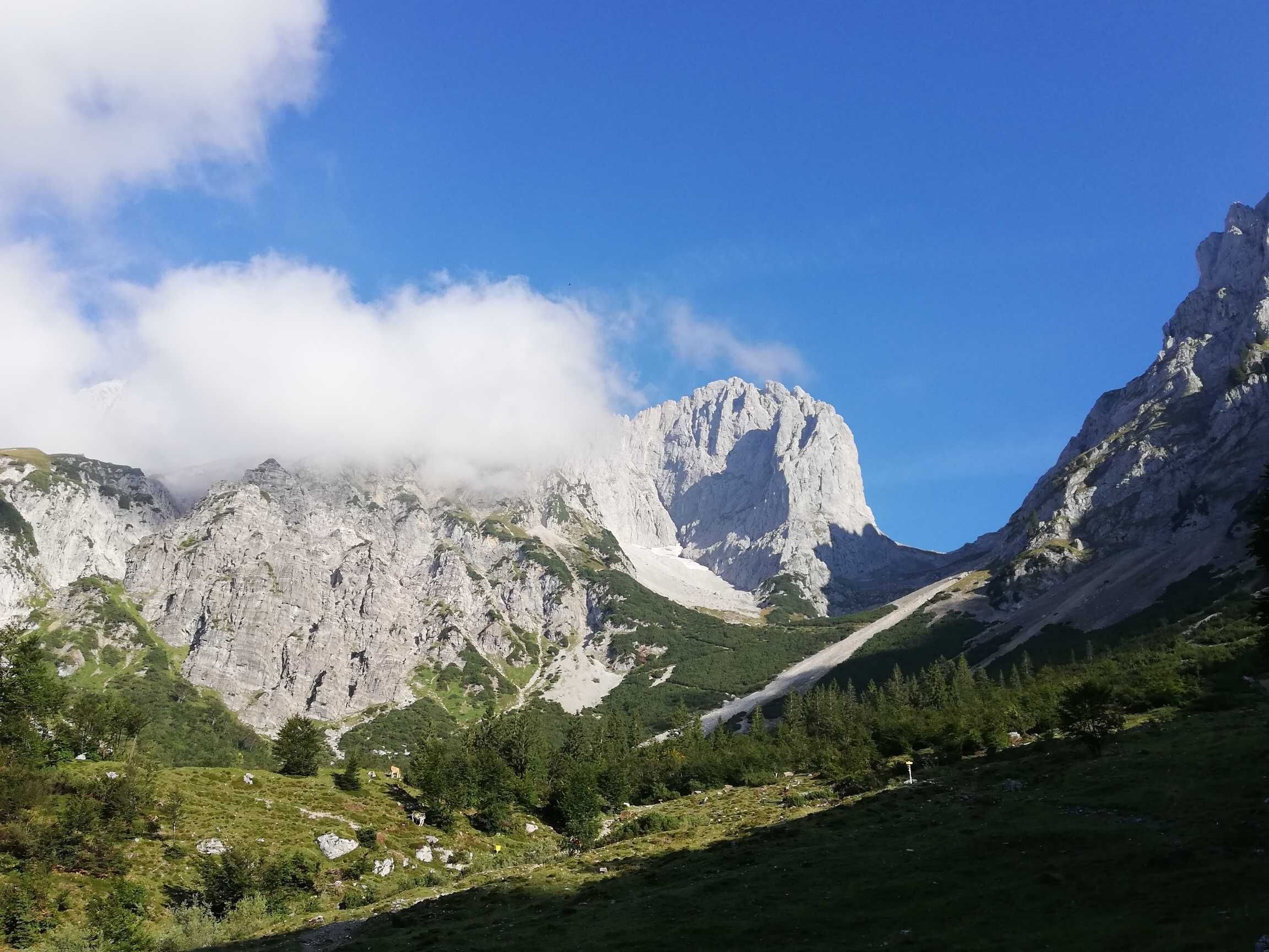 Un paysage montagneux caractérisé par un sommet rocheux imposant, une vallée verdoyante et un ciel dégagé.