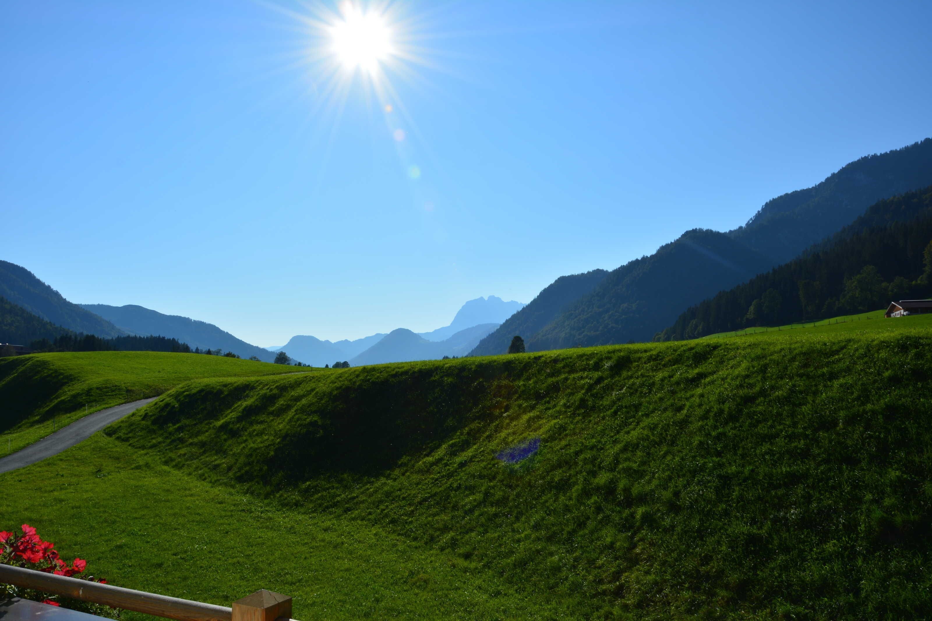 Un paysage rural avec une route, des collines verdoyantes et un ciel dégagé.