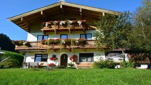 Un chalet traditionnel doté d’un balcon en bois, d’une entrée principale et d’un petit jardin.
