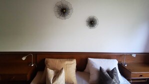 Une chambre d’hôtel avec un lit, deux éléments de décoration murale et une table de chevet avec une lampe.