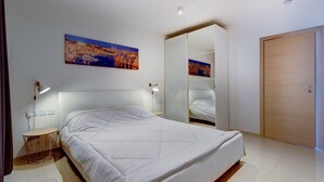 Un dormitorio con cama, lámparas de noche, un espejo y una puerta.