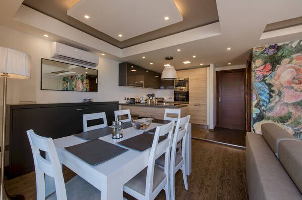 Une cuisine moderne avec des meubles blancs, une table à manger avec des chaises et un grand miroir au-dessus du comptoir.