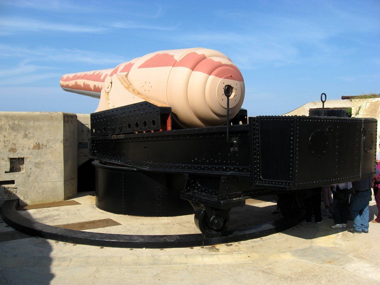 Ein großes, feststehendes Objekt, das einer Schildkröte mit einem zylindrischen Panzer ähnelt und auf einer rollbaren Plattform angebracht ist.