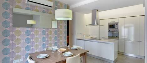 A modern kitchen with a central island, built-in appliances, and a dining area with a table set for two.