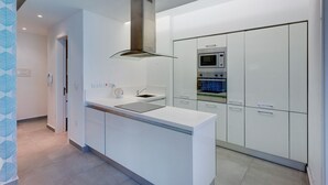 Una cocina moderna con armarios blancos, un horno de acero inoxidable y un microondas integrado.