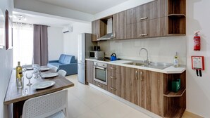 Eine kleine Küche mit Holzausbau, einer eingebauten Mikrowelle und einem Edelstahl-Spülbecken.
