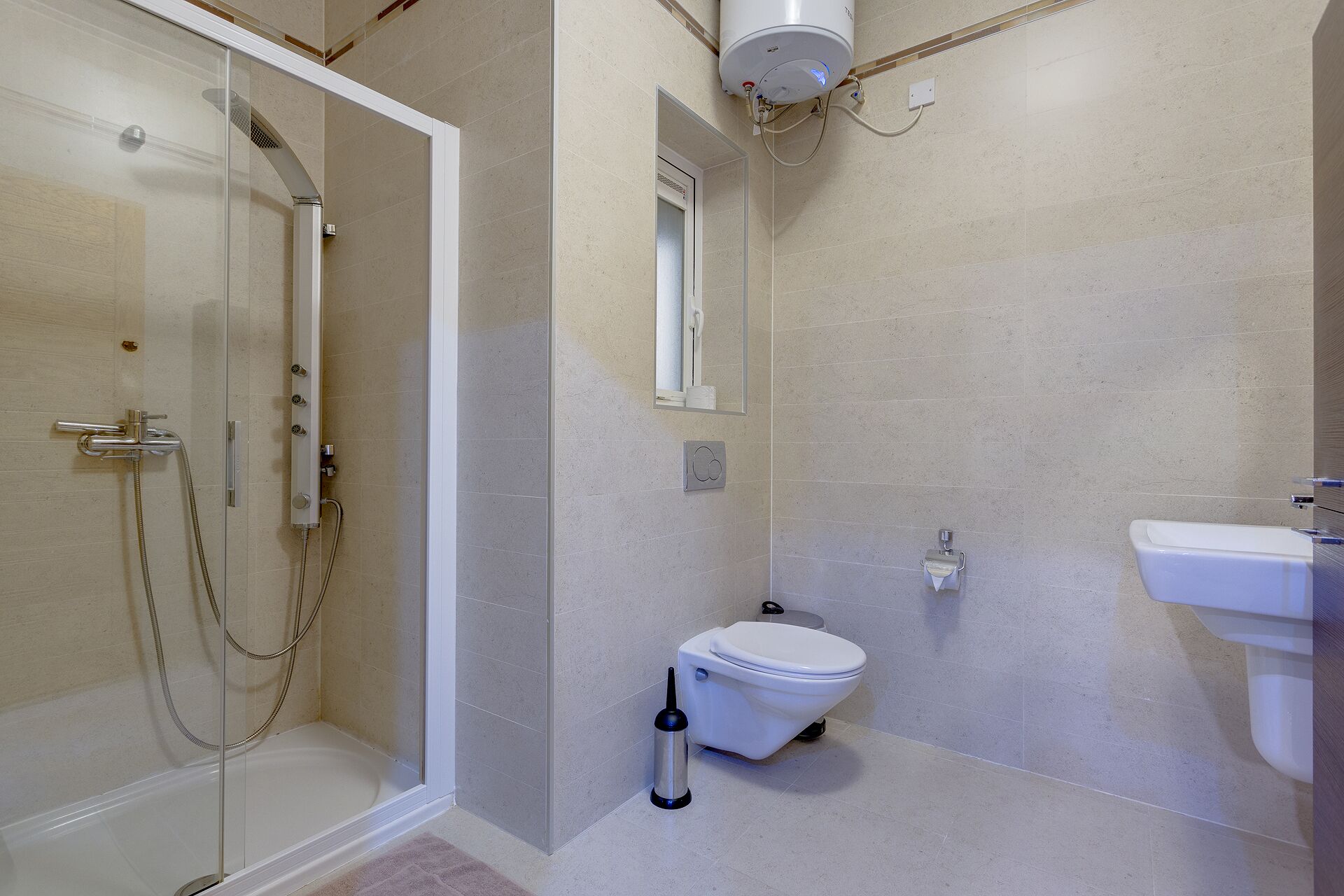 A bathroom with a glass-enclosed shower, a toilet, and a sink.