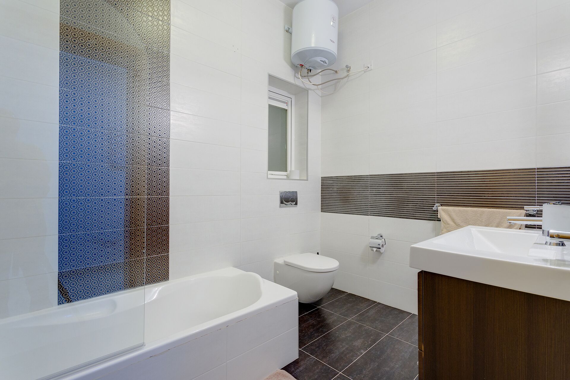 A modern bathroom with a bathtub, toilet, and vanity.