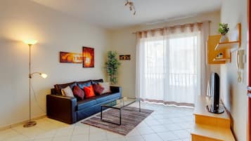 A living room with a sofa, coffee table, floor lamp, and artwork on the walls.