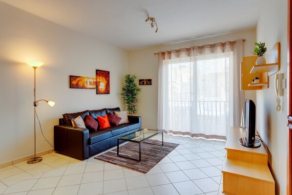 A living room with a sofa, coffee table, floor lamp, and artwork on the walls.