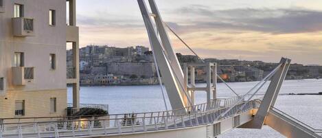 A modern pedestrian bridge with a clear view of the cityscape and waterfront in the background.