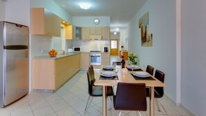 Eine moderne Küche mit Kühlschrank, Mikrowelle, Herd und Essbereich mit Tisch und zwei Stühlen.